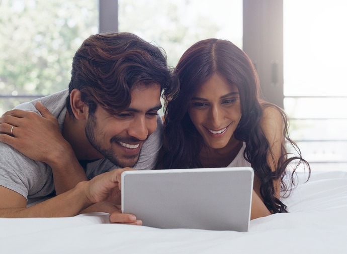 Man and woman laughing while looking at a tablet